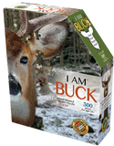 A puzzle box with text that says, "I Am Buck. Head-shaped jigsaw puzzle. 17" x 24". 300 pieces. For ages 10+." There is a picture of a buck on the side of the box with puzzle pieces coming out of it.
