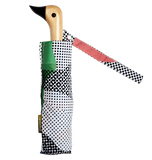 A black and white spotted umbrella with a duck head at the top of the pole with a black beak.