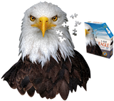 A puzzle that is shaped like an eagle. There are puzzle pieces missing from it and some next to the side of its head. Next to it is a puzzle box with text that says, "I Am Eagle. Head-shaped jigsaw puzzle. 17" x 24". 300 pieces. For ages 10+." There is a picture of an eagle on the side of the box with puzzle pieces coming out of it.