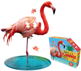 A puzzle that is shaped like a flamingo. There are puzzle pieces missing from it. Next to it is a puzzle box with text that says, "I Am Lil' Flamingo. Animal-Shaped jigsaw puzzle. Poster size! 100 pieces. For ages 5+." There is a picture of a flamingo on the side of the box with puzzle pieces coming out of it.