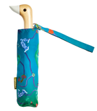 A blue umbrella with a design of various fungi around with a duck head at the top of the pole with a white beak.