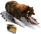 A puzzle that is shaped like a Grizzly bear that is attempting to eat a fish. There are puzzle pieces missing from it. Next to it is a puzzle box with text that says, "I Am Grizz. Animal-shaped jigsaw puzzle. Poster size! 300 pieces. For ages 10+." There is a picture of a Grizzly bear on the side of the box with puzzle pieces coming out of it.