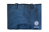 A blue tote bag with the embroidered logo for ISM, which is an anchor sitting on a wave encompassed by a circle that is surrounded by stars, and the words, "Independence Seaport Museum."