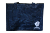 A navy-blue tote bag with the embroidered logo for ISM, which is an anchor sitting on a wave encompassed by a circle that is surrounded by stars, and the words, "Independence Seaport Museum."