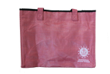 A pink tote bag with the embroidered logo for ISM, which is an anchor sitting on a wave encompassed by a circle that is surrounded by stars, and the words, "Independence Seaport Museum."