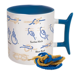 A white mug with a blue inside and a blue handle that has illustrations on how to tie knots on it. The side of the mug facing the camera has instructions on tying a bowline, a tautline hitch, and a sheet bend. There is some rope next to the mug to practice tying knots with.