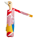 A colorful umbrella with different shapes on the base with a duck head at the top of the pole with a white beak.
