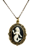 A black pendant on a necklace chain with a white mermaid in the center. The outside is gold with an ornate design.