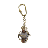 A brass keychain featuring a miniature vintage lantern charm with a carabiner clasp