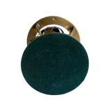A round dark green velvet or suede-covered knob with a polished gold metal backplate