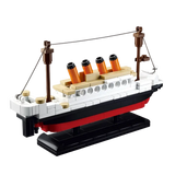 Toy building block model of the Titanic, featuring white, black, and red ship body, beige and orange smokestacks, and a black display base 