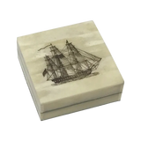 A square cream-colored wooden box with a lid, featuring a detailed black engraving of a multi-masted sailing ship on top
