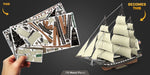 Card with ship design on one side and completed ship model on the other, held by a hand.