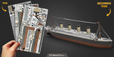 Hand holding a set of Titanic model building pieces with completed model in the background