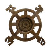 Back of a vintage-style brass compass wheel paperweight with ornate directional figures at the ends of each arm