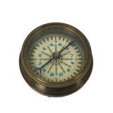 A vintage brass compass with a detailed printed dial showing traditional Chinese direction symbols and cardinal directions