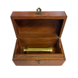 A brass telescope eyepiece or lens resting inside an open wooden presentation box with a hinged lid and brass latch