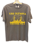 A dark gray crewneck t-shirt hanging on a wooden hanger against a textured gray wall. The shirt features a yellow graphic print of the USS Olympia Cruiser No.