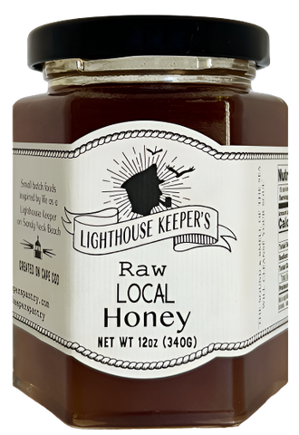 A jar of raw honey. There is a white label across the front that has an illustration of the silhouette of a sailor's face. He is smoking a cigar and wearing a hat. There are two birds flying over him. Underneath the sailor's face, there is a banner that says, "Lighthouse Keeper's." Underneath that, there is text that says, "Raw local honey." 