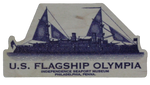 A tan magnet with a blue depiction of the Olympia on it. There is blue text underneath the Olympia that reads, "U.S. Flagship Olympia. Independence Seaport Museum. Philadelphia, Penna." 