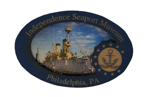 A wooden magnet that shows an image of the Cruiser Olympia on it, along with text that says, "Independence Seaport Museum. Philadelphia, PA," along with the ISM logo, which is an anchor floating on some waves encompassed in a circle and surrounded by stars. 