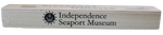 The words "Independence Seaport Museum" and the ISM logo, which is an anchor sitting on a wave encompassed by a circle that is surrounded by stars, are on the back of a wooden riverboat whistle. 