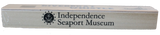 The words "Independence Seaport Museum" and the ISM logo, which is an anchor sitting on a wave encompassed by a circle that is surrounded by stars, are on the back of a wooden riverboat whistle. 