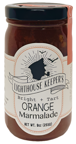 A jar of orange marmalade. The jar has a white label on it with the silhouette of a sailor's face who is smoking a cigar. Around him are two birds. There is an illustrated banner underneath him that says, "Lighthouse Keeper's." Underneath that, it says, "Bright + Tart orange marmalade." 