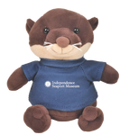 A small plush otter wearing a shirt that says "Independence Seaport Museum" with a logo of an anchor that is surrounded by a circle with stars around the outside of it.