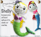 Two string dolls of mermaids. One has yellow hair, pale skin, a purple bra, and a green tail. The other has red hair, pale skin, a pink bra, and a blue tail. There is text next to the string dolls that says, "Shelly keeps you afloat when it's sink or swim."