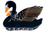 A claw clip of a black swan. The swan has a black body with golden outlines on its feathers, a white face, and an orange beak. 