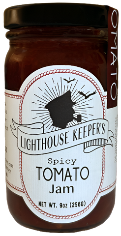 A jar of tomato jam. There is a white label on it with an illustration of the silhouette of a sailor's face, who is smoking a pipe. There are two birds flying above him. There is a banner underneath him that says, "Lighthouse Keeper's." Underneath that, it says, "Spicy tomato jam."