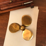 Gold propeller model on a white sheet of paper with a wooden background